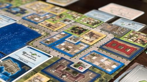 Lähikuva Cities: Skylinesin pelilaudasta, jolla on rakennuslaattoja ja kortteja.